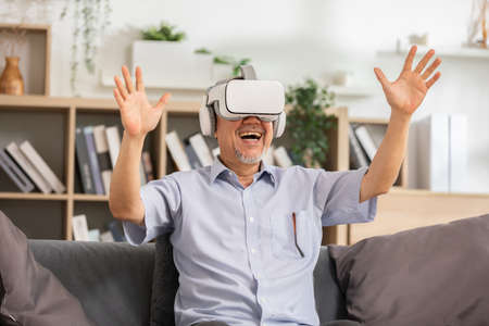 Happy elderly using VR or Virtual Reality glasses headset pointing objects or talking in community...