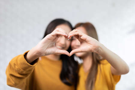 LGBTQ Asian lesbian couple making heart shape sign hug and smiling with love together.Homosexual couple embracing and looking at camera.Cute girl smiling and looking camera.LGBTQ Lifestyle Pride Monthの写真素材