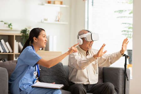 Asian Female doctor give advice elderly patient using VR or Virtual Reality glasses headset pointing...