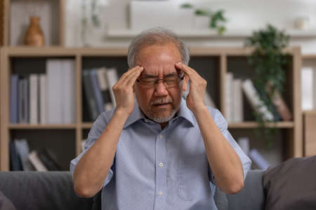 Asian elderly seniority man got headache and migraine. Old man got pain and illness on couch alone...