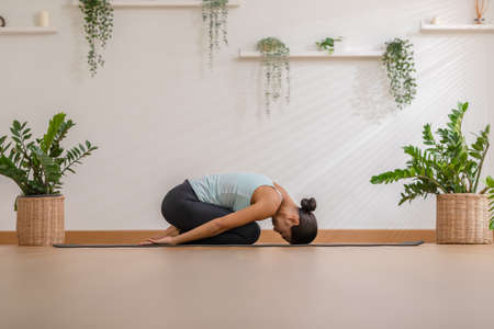 Side view of Asian woman wearing green sportwear doing Yoga exercise,Yoga Childâs pose or Balasana,Calm of healthy young woman breathing meditation with yoga at home,Exercise for wellness lifeの写真素材