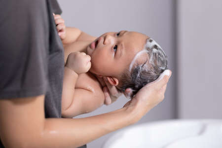 Calm of asian newborn baby bathing in bathtub.mother bathing her son in warm water.Happy adorable...