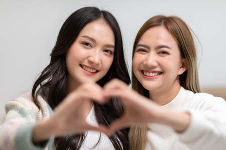 LGBTQ Asian lesbian couple making heart shape sign hug and smiling with love together.Homosexual couple embracing and looking at camera.Cute girl smiling and looking camera.LGBT Lifestyle Pride Monthの写真素材