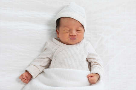 Top view happy newborn baby lying sleeps on a white blanket comfortable and safety at warmth place....
