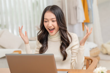 Entrepreneur beautiful business asian young woman working online with laptop and celebrating at home with her work success cheerful and happiness. Small Business Startup concept. Surprise and exciteの写真素材