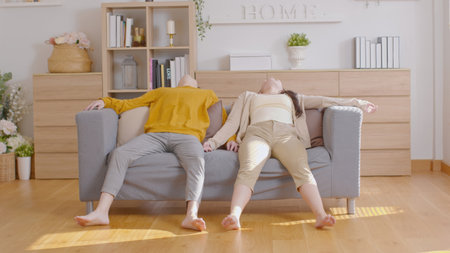 Asian couple love resting and relax on sofa or couch after moving sofa into new home. Lovers lying on couch together in holidays at homeの写真素材