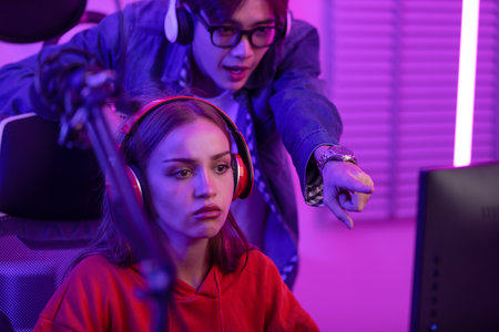 Couple of gamer boyfriend couching and guide girlfriend playing online streaming game together. Professional lover live streaming at home. Couple gamer conceptの写真素材