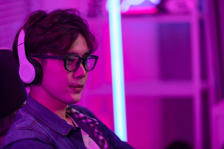 Asian gamer with a happy expression in front of a computer screen, lokking in computer screen and concentrate with online video game. Professional gamer conceptの写真素材