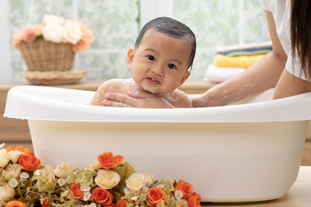 Adorable of asian newborn baby bathing in bathtub.mother bathing her son in warm water.Happy...