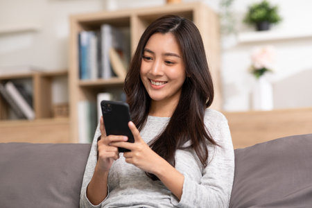 Happiness Entrepreneur beautiful business asian young woman wear casual use mobile phone for shopping online enjoy with social media and laptop at home.Small Business Startup.online bankingの写真素材