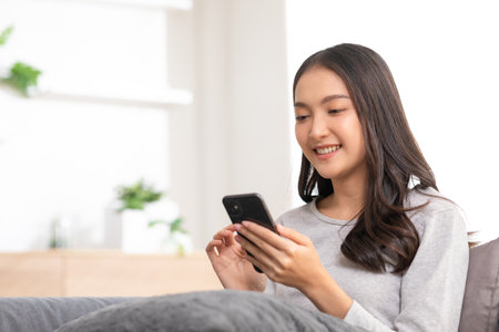 Happiness Entrepreneur beautiful business asian young woman wear casual use mobile phone for shopping online enjoy with social media and laptop at home.Small Business Startup.online bankingの写真素材
