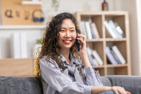 Asian young woman answer the phone and talking with positive and happiness emotional.Attractive female talkin in smartphone smile and cheeful with good news and good moment at homeの写真素材