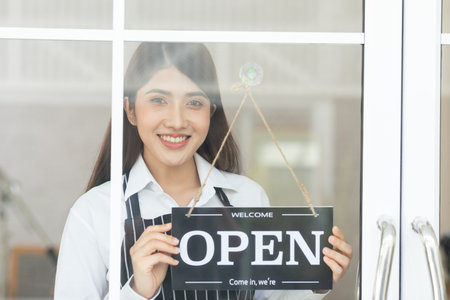 Female owner turning sign board to open coffee shop smile and happiness. Smiling asian woman open...