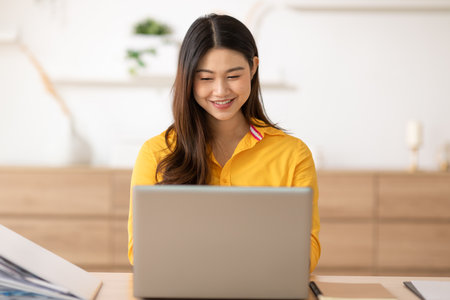 Entrepreneur beautiful business asian young woman wear yellow shirt work online with laptop at home.Freelance female working online sale marketing at home.Small Business Startup conceptの写真素材