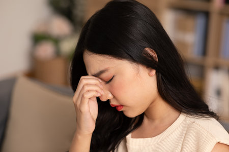 Asian young Woman has a Migraine and headache after wake up in cozy bedroom at home,Suddenly of painful attack on head massage around on pain spot,Healthcare Conceptの写真素材