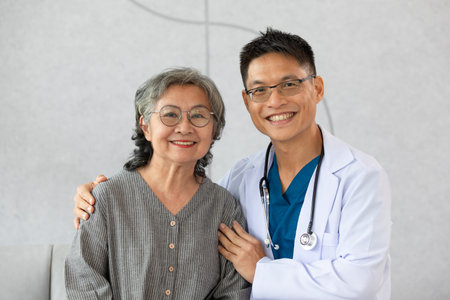Happy doctor and elderly patient smile and looking camera nursing at home. Asian senior woman and doctor giving care and empathy to patient or retirement in homecare service. Elderly care conceptの写真素材