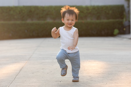 Joyful Toddler Running Outdoors in Sunlightの写真素材