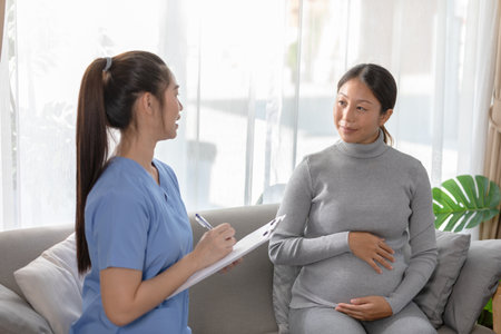 Asian pregnant woman is having consultation with healthcare professional in cozy home setting. The...