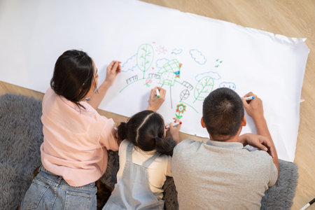 Heartwarming scene of Asian family spending quality time together at home. The father, mother, and their young daughter are lying on the floorの写真素材