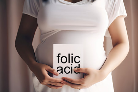 Pregnant woman holding a card with the text folic acid.の素材