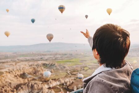 Asian man watching colorful hot air balloons flying over the valley at Cappadocia, Turkey This Romantic timeの写真素材