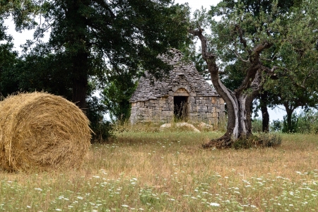 Trulli hut in field with hay baleの写真素材