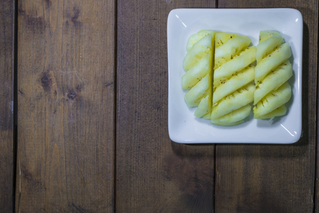 Top view pineapple chucks in a bowl on wooden tableの写真素材