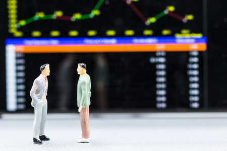 Miniature people : small figures businessmen stand and look at Stock Exchange Board Background with copy space and using as background finance business team competition concept, business plan concept.の写真素材