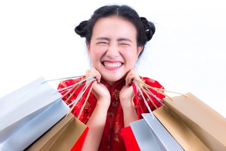 Young asian woman wearing chinese dress traditional cheongsam with Carrying a shopping bag and smile. Chinese New Year Festivities, New Year Celebration, Shopping concept, on white background.の写真素材
