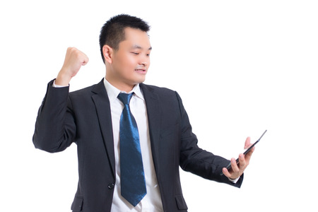 Closeup businessman wear black suit. Hand holding blank screen digital tablet blank copy space screen for your text message or promotional content against desktop.の写真素材