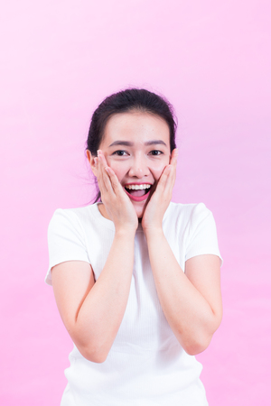 Portrait of beautiful Young Asian woman black hair wear a white t-shirt. with shocked facial expression. Portrait of surprised beautiful girl holding her head in amazement and open-mouthed.の写真素材