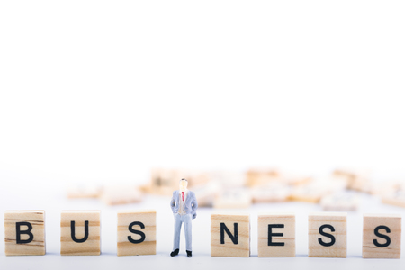 Business leader concept. Miniature people small figure standing in the middle wooden cube with word business on white background. With copy space. Teamwork, Management, Businessman, leadershipの写真素材