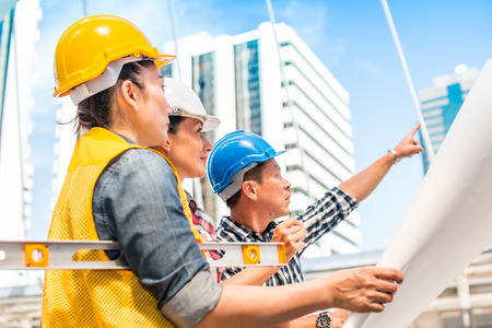Three industrial engineer wear safety helmet engineering working and talking with drawings...