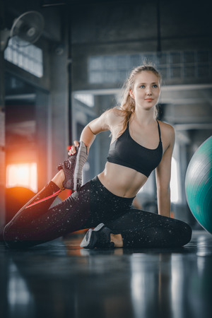 Young attractive woman fitness doing exercises workout with ball in gym. Woman stretching the muscles and relaxing after exercise at fitness gym club.の写真素材
