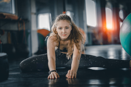 Young attractive woman fitness doing exercises workout with ball in gym. Woman stretching the muscles and relaxing after exercise at fitness gym club.の写真素材