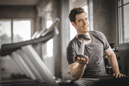 Fit caucasian handsome young man and big muscle in sportswear. Young man holding dumbbell during an exercise class in a gym. Healthy sports lifestyle, Fitness concept. with copy space for your text.の写真素材
