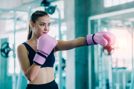 Fit beautiful woman boxer hitting a huge punching bag exercise class in a gym. Boxer woman making direct hit dynamic movement. Healthy, sports, lifestyle, Fitness, workout concept. With copy space.の写真素材