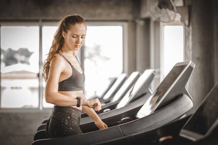 Fit young woman caucasian running on machine treadmill workout in gym. Glad smiling girl is enjoy with her training process. Concept of fitness, healthy life, Sport, Lifestyle.の写真素材