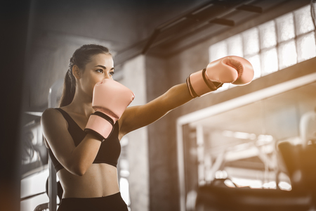 Fit beautiful woman boxer hitting a huge punching bag exercise class in a gym. Boxer woman making direct hit dynamic movement. Healthy, sports, lifestyle, Fitness, workout concept. With copy space.の写真素材