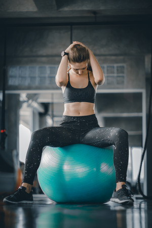 Young attractive woman fitness doing exercises workout on ball in gym. Woman stretching the muscles and relaxing after exercise at fitness gym club.の写真素材