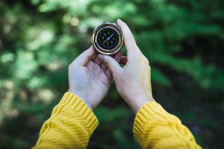 Female hands hold a compass in the forest. Travel and adventure concept.の写真素材