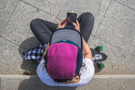 woman with cap and skateboard with mobile phoneの写真素材