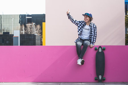 woman with cap and skateboard with mobile phoneの写真素材