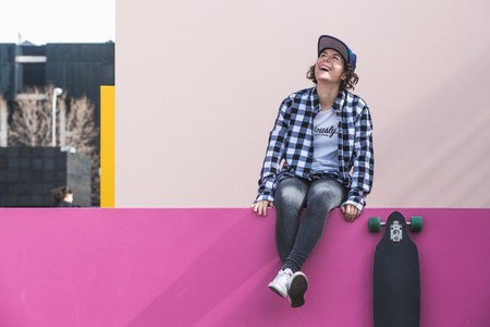 woman with cap and skateboard with mobile phoneの写真素材