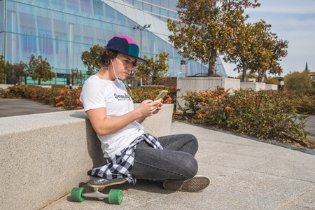 woman with cap and skateboard with mobile phoneの写真素材