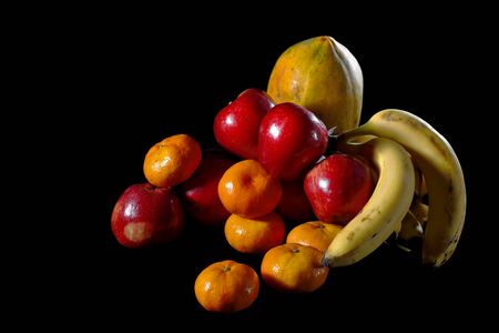 Arrangement of fruit still life with black background and tropical fruits such as papaya, apple, tangerine and bananasの写真素材