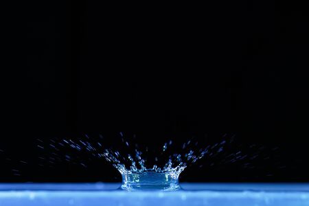 Sculpture of water in the shape of a crown generated after the drop of a drop on a mass of water at...