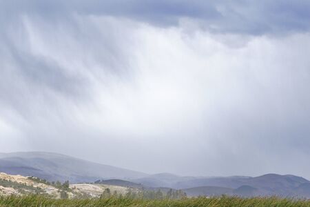 View of the rain falling in the distance on the horizon over the Andean mountainsの写真素材