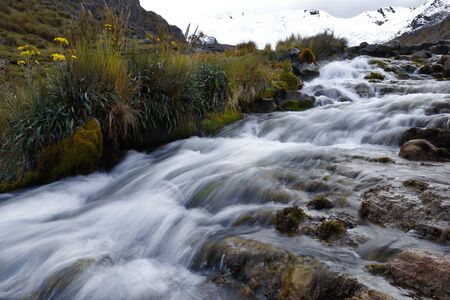 View on a cloudy day of the snowy Huaytapallana next to a small river in the central mountain range...