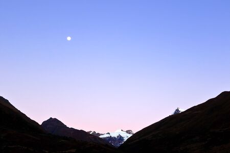 Beautiful sunrise witnessed from the Huaytapallana mountain range next to the moon.の写真素材